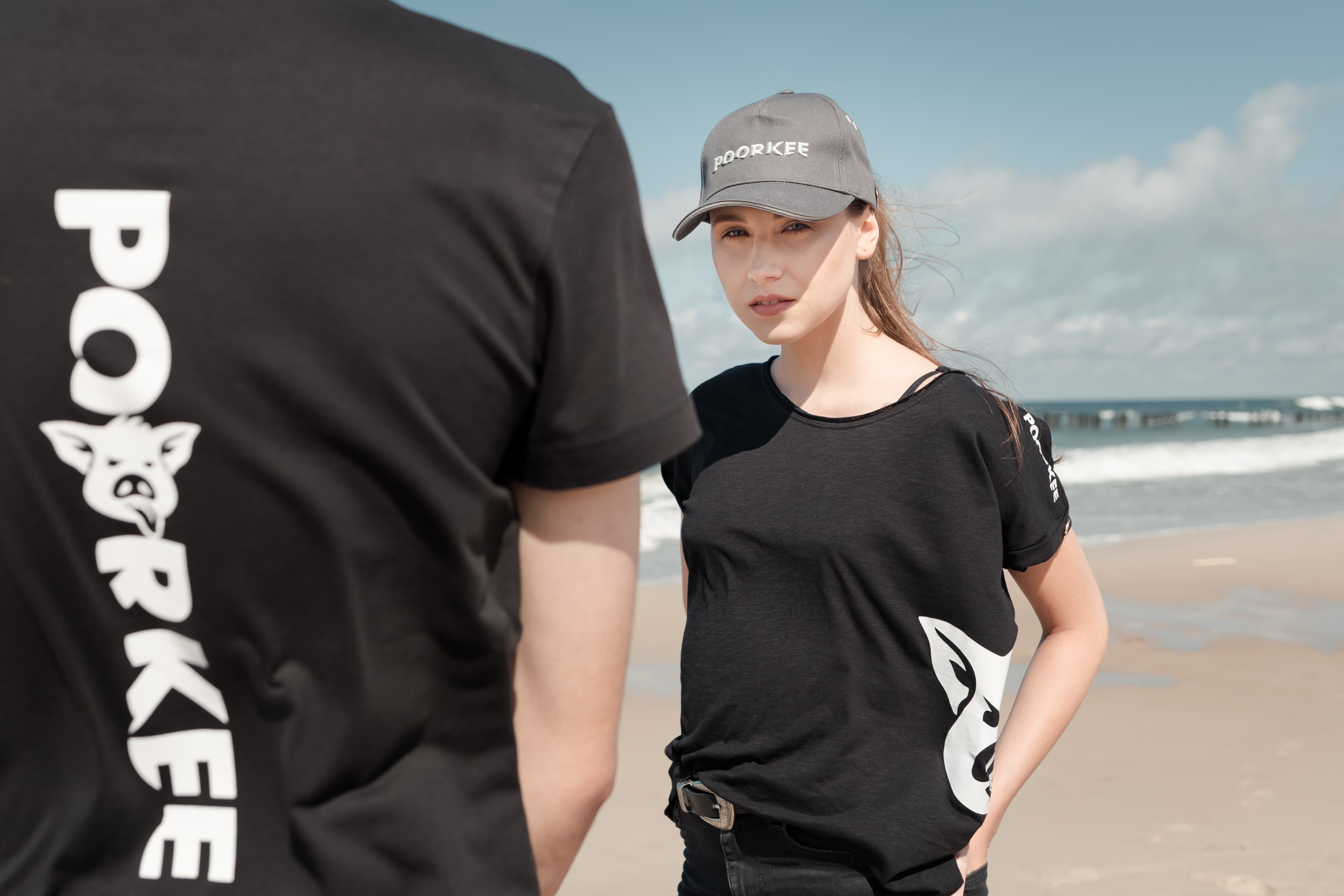 a girl in a black T-shirt and a gray baseball cap on the beach looks at the camera