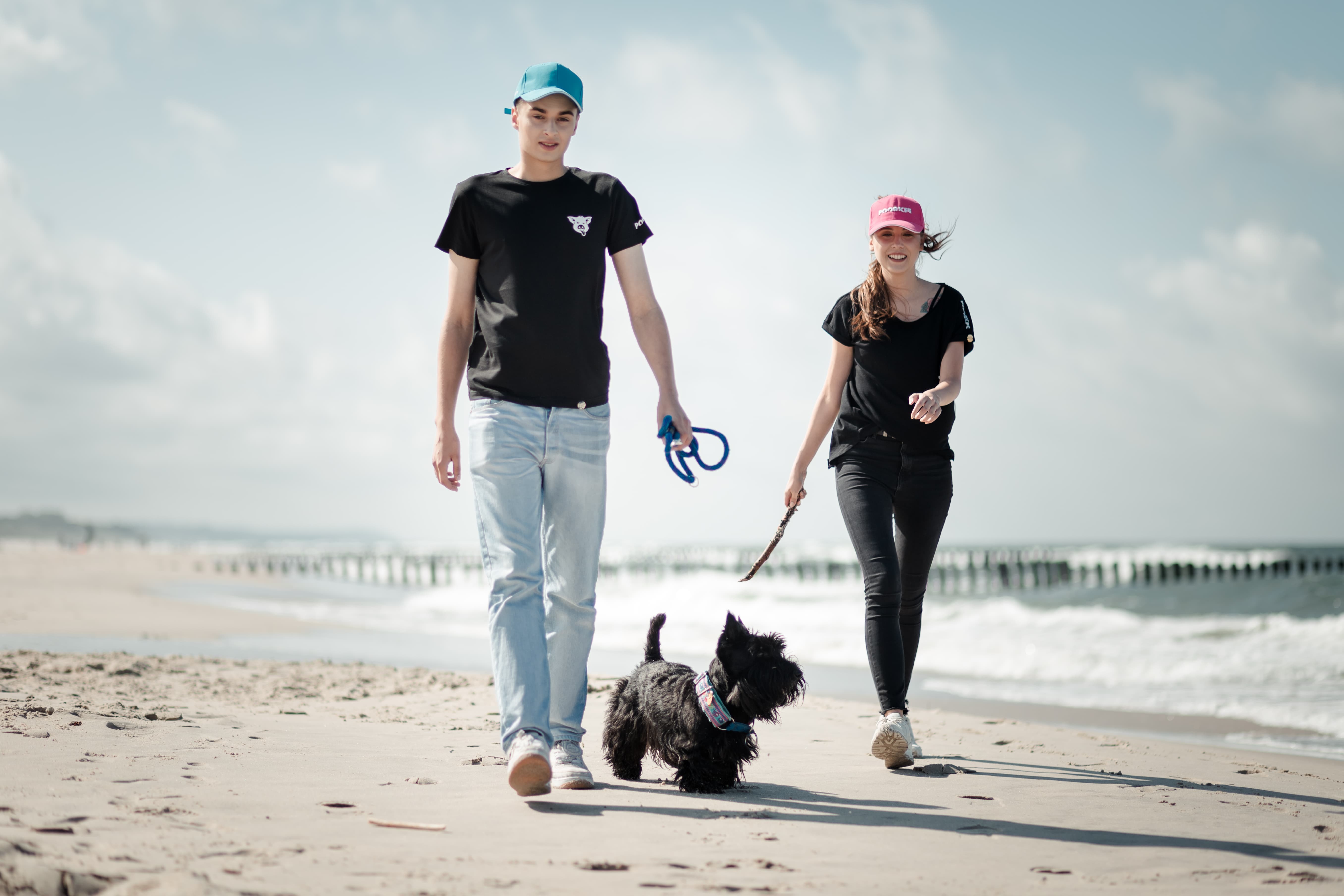 boy and girl are walking on the beach with a dog