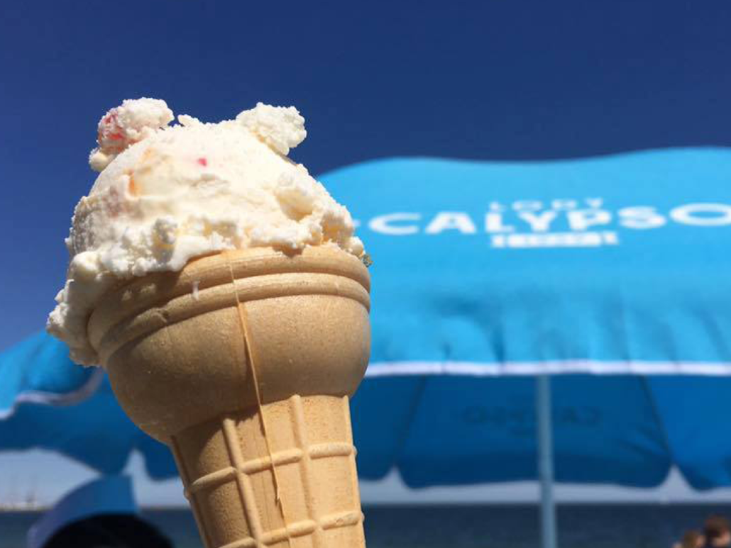 white scoop of ice cream in a wafer, in the background a blue Calypso umbrella